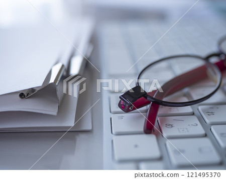 Documents, keyboard and glasses on a table 121495370
