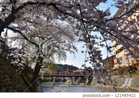 Takayama City, Gifu Prefecture, Japan, Spring Takayama Festival, Cherry blossoms in full bloom and food stalls crossing Nakabashi Bridge, beautiful fresh greenery, blue sky and Miyagawa River 121495422
