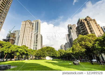 Low-angle view of green park space and modern buildings on both sides in downtown Taichung, Taiwan, It is near the National Taichung Theater. Low-angle view of green park space and modern buildings on both sides in downtown Taichung, Taiwan, It is near the National Taichung Theater. 121495529