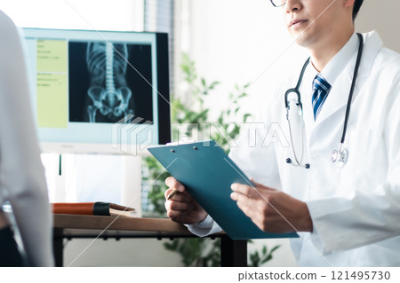 A male doctor conducting a medical interview and a female patient holding her waist A male doctor conducting a medical interview and a female patient holding her waist 121495730