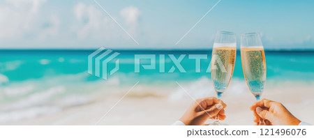 Banner. Two champagne glasses held against turquoise sea and sky background, bubbles sparkling in sunlight. Copy space. 121496076
