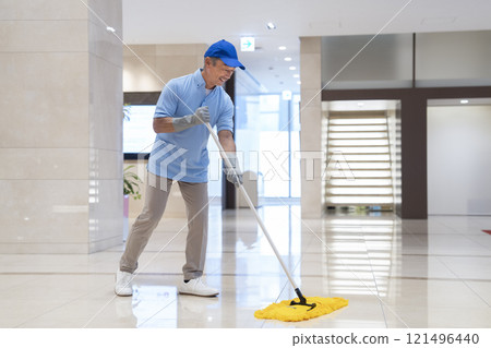 Image of building cleaning: Male cleaning staff in their 60s wiping the floor with a mop 121496440