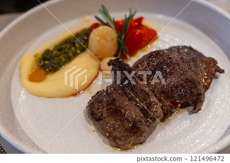 Juicy grilled beef served with creamy mashed potatoes, roasted tomatoes, and garnished with herbs. 121496472