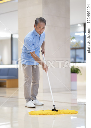 Image of building cleaning: A man in his 60s wiping the floor with a mop 121496494