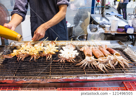 Close-up of the vendors grilling squid skewers at the night market in Taiwan.  121496505