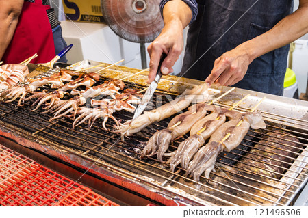 Close-up of the vendors grilling squid skewers at the night market in Taiwan.  121496506