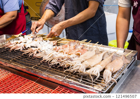 Close-up of the vendors grilling squid skewers at the night market in Taiwan.  121496507
