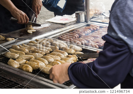 Close-up of the vendors grilling Taiwanese sausage and sticky rice (glutinous rice) sausage in the night market in Taiwan. This is one of the street snacks popular among tourists in Taiwan. 121496734