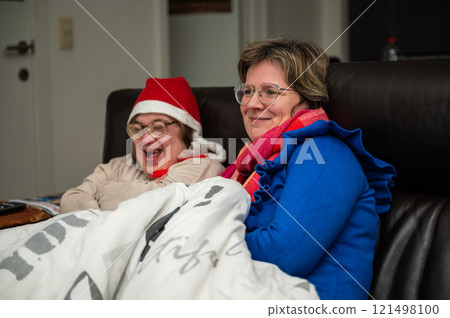 Cosy moment of a 42 yo woman with the Down Syndrome and her 38 yo female friends, at home, Brussels, Belgium 121498100