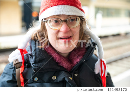 Outdoor portrait of a 42 yo woman with Down Syndrome, wearing a christmas hat in a railway station, Brussels, Belgium 121498170