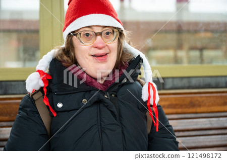 Outdoor portrait of a 42 yo woman with Down Syndrome, wearing a christmas hat in a railway station, Brussels, Belgium 121498172