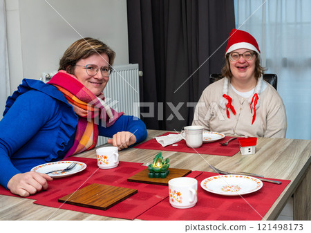 Cosy moment at the dining table during Christmas celebration with a 42 yo Down Syndrome woman and her 38 yo friend, Belgium 121498173