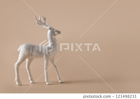 Christmas silver deer figurine stands against beige background. Color of New 2025 Year Mocha Mousse. Copy space. Xmas card 121498231