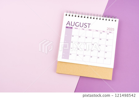 August 2025 desk calendar on pink and purple background. 121498542