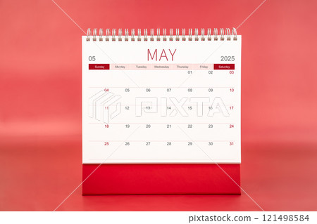May 2025 blank desk calendar on red color background. 121498584