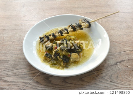 baking cherry or golden apple snail stabbing wooden stick dressing Thai spicy seafood sauce on plate baking cherry or golden apple snail stabbing wooden stick dressing Thai spicy seafood sauce on plate 121498890