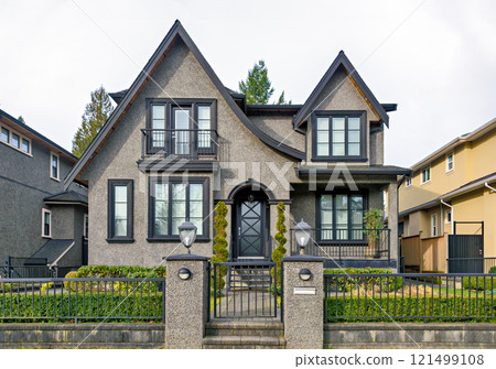 Gloomy residential house with metal fence in front on overcast sky background 121499108