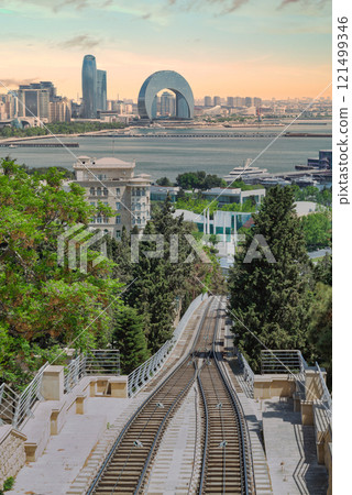 View of Baku Funicular railway amid greenery with city skyline and Caspian Sea in the background 121499346