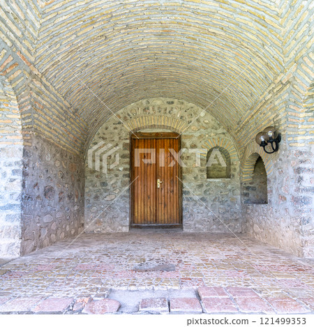 Stone archway with rustic wooden door, and vaulted brick ceiling at the Upper Caravanserai courtyard, Shaki, Azerbaijan 121499353
