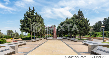 The Turkish Martyrs Memorial in Baku, Azerbaijan, stands tall with Turkish and Azerbaijani flags waving in the breeze 121499358
