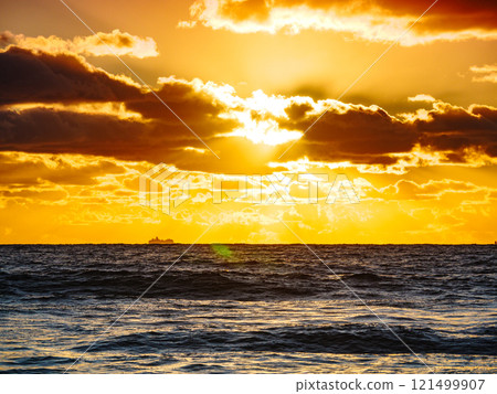 Sea at sunset with cargo ship on horizon Sea at sunset with cargo ship on horizon 121499907