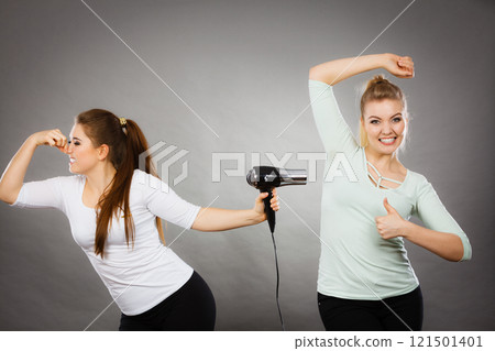 Woman drying friend armpit with hair dryer Woman drying friend armpit with hair dryer 121501401