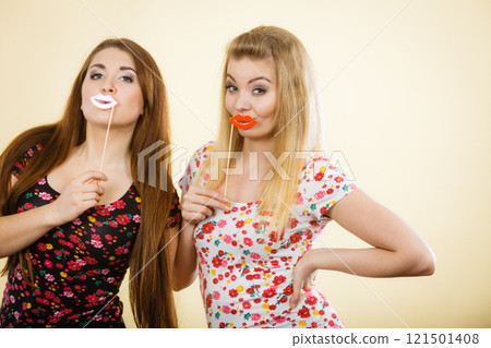 Two happy women holding fake lips on stick 121501408