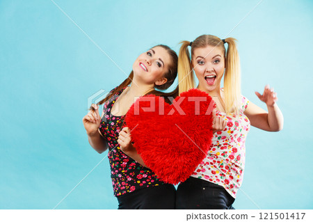Happy two women holding heart shaped pillow 121501417