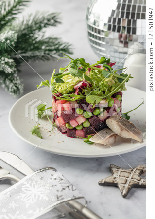 Traditional Russian and Ukrainian vegetable salad Vinaigrette for celebrating new year. Salad with beets, potatoes, cucumbers and peas served with slices of herring 121501942