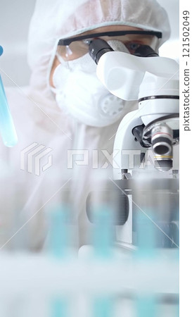 Scientist in ppe analyzing samples and analyzing samples with a microscope in a laboratory setting, portrait. Science concept 121502049