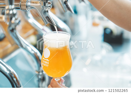 A female clerk pouring beer from a dispenser. Photo courtesy of Tsukioka Brewery. 121502265