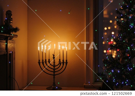 Minimal background image of glowing menorah candles with Christmas lights and decorations in elegant warm lit setting copy space 121502669