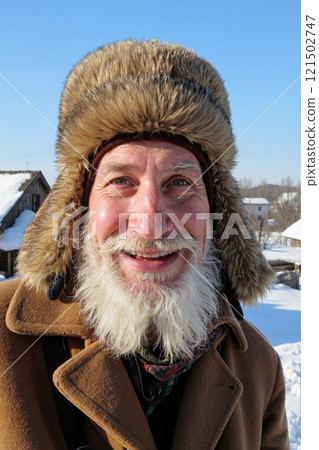 Vertical closeup portrait of bearded senior man wearing fur hat and smiling at camera enjoying bright winter day outdoors 121502747