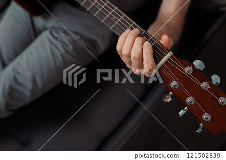man guitarist playing guitar at home. Relaxing and sitting on sofa 121502839