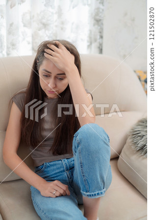 Young woman experiencing headache while sitting on a couch in a modern living room home during daytime vertical photo Young woman experiencing headache while sitting on a couch in a modern living room home during daytime vertical photo 121502870