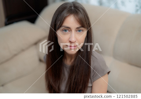peace woman sitting comfortably on a gray couch at home, smiling and relaxing in soft natural light during the afternoon peace woman sitting comfortably on a gray couch at home, smiling and relaxing in soft natural light during the afternoon 121502885