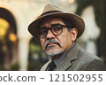 Close up portrait of senior professor wearing glasses and fedora hat looking away with thoughtful face expression copy space 121502955