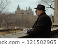 Side view portrait of senior professor wearing coat and hat looking out to historic university campus with cloudy sky in background copy space 121502965