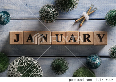 The word January in English is made of wooden blocks. Christmas tree figures, ski ornament, blue wooden background. The word January in English is made of wooden blocks. Christmas tree figures, ski ornament, blue wooden background. 121503006