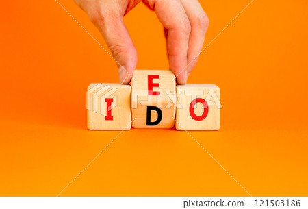 Initial exchange or DEX offering symbol. Concept words abbreviation IEO or IDO on wooden block. Beautiful orange table orange background. Business Initial exchange or DEX offering concept. Copy space. 121503186