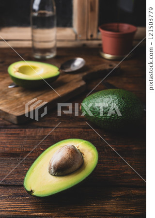 Green halved avocado on rustic kitchen table Green halved avocado on rustic kitchen table 121503779