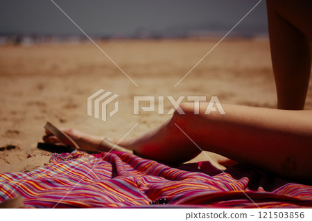 A woman's feet, legs on a warm sand. A woman, girl resting on a sandy coast, beach on pink plaid in summer. Summertime vacations by the sea, ocean. 121503856