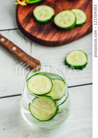 Water infused with sliced cucumber 121504303