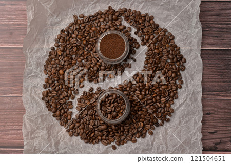 Fresh aromatic grain and ground coffee in transparent glasses on craft paper, wooden table. Composition in the form of yin yang 121504651