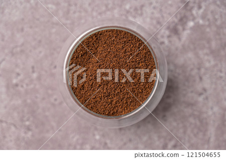 Top view closeup fresh aromatic ground coffee in a small glass on a gray concrete background 121504655