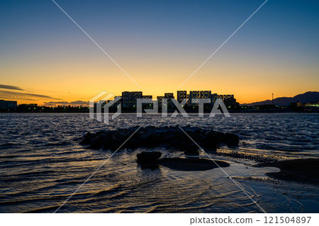 A seaside scene with the silhouette of the Yaichi apartment building. Photographed at Kohroenhama Beach in Nishinomiya City. 121504897
