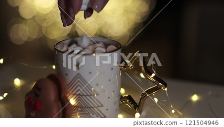 A woman puts marshmallows in a glass of cocoa. Christmas, New Year concept background. 121504946