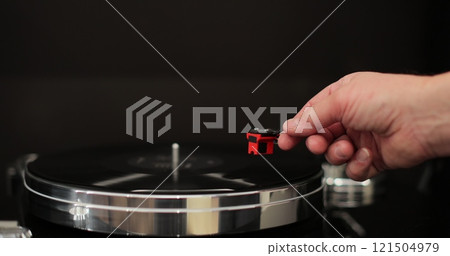 Male hands operating vinyl record player with a vinyl disc. The needle rises from a vintage vinyl record. The vinyl record is spinning. Male hands operating vinyl record player with a vinyl disc. The needle rises from a vintage vinyl record. The vinyl record is spinning. 121504979