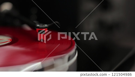 Male hands operating vinyl record player with a vinyl disc. The needle rises from a vintage vinyl record. The vinyl record is spinning. Male hands operating vinyl record player with a vinyl disc. The needle rises from a vintage vinyl record. The vinyl record is spinning. 121504986