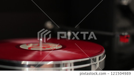 Man places a red disk on a vinyl player. Vinyl record gets placed on a turntable. Classic vinyl record player. Man places a red disk on a vinyl player. Vinyl record gets placed on a turntable. Classic vinyl record player. 121504989